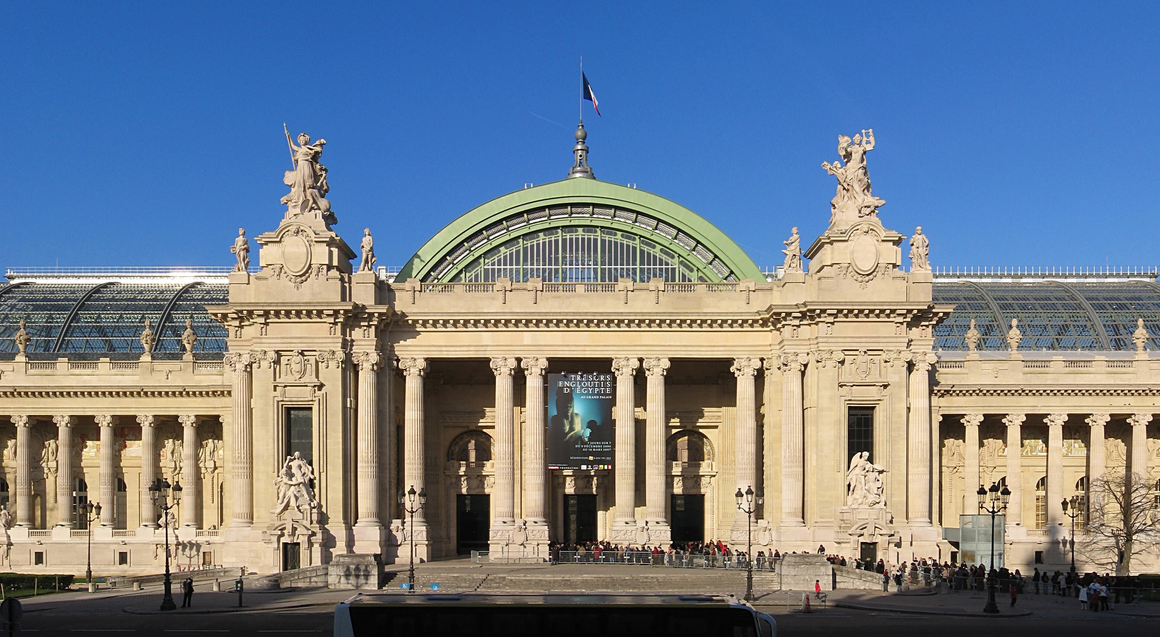 Façade du Grand Palais, nef de verre verte, colonnes, file d’attente et affiche d’exposition au tympan.